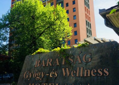 Hotel márványtábla aranybetűkkel háttérben épülettel