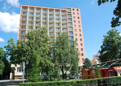 Hotel épülete előtérben zöld fákkal